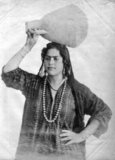Photograph of an Arab woman of Algeria carrying a water pot on her head. Produced as a souvenir for the nascent European tourist market.